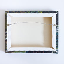 Load image into Gallery viewer, The back of a canvas reproduction of a painting. The canvas wraps around the back and is stapled onto the wood frame. A hanging wire is attached to two hinges mounted on the frame. There are two rubber circles stuck to the bottom corners of the canvas.
