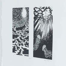 Load image into Gallery viewer, A side, angled view of a black and white linocut diptych print. There are two images, the first of a boat sitting on the water at nighttime, reflecting the light of the moon. The second is of the light illuminating two jellyfish underneath the water.
