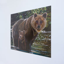 Load image into Gallery viewer, A side view of a paper reproduction of a painting. The painting features two grizzly bears, a mother, and her young cub crossing a river. They are standing in shiny green and turquoise water, and there is a blurry green background behind them.
